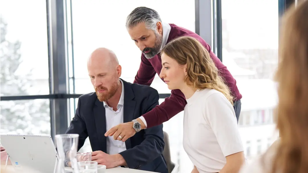 Colleagues in a conference room, looking at a laptop