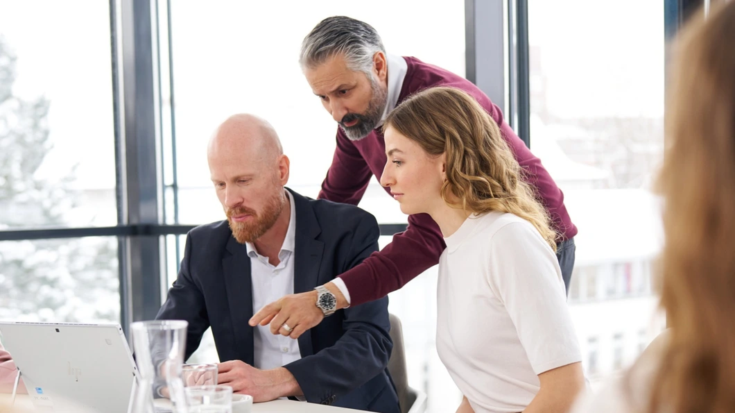 Colleagues in a conference room, looking at a laptop